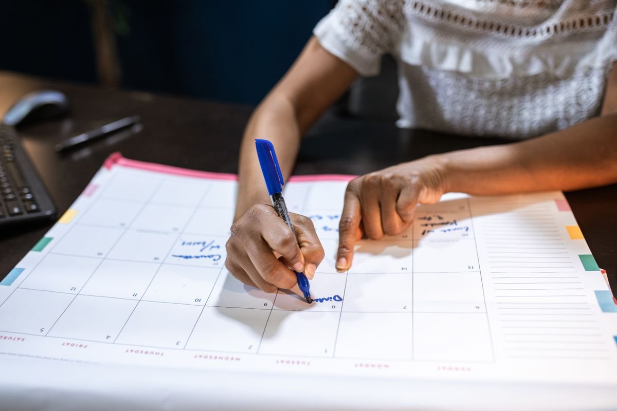 Mulher marcando datas importantes em calendário de mesa