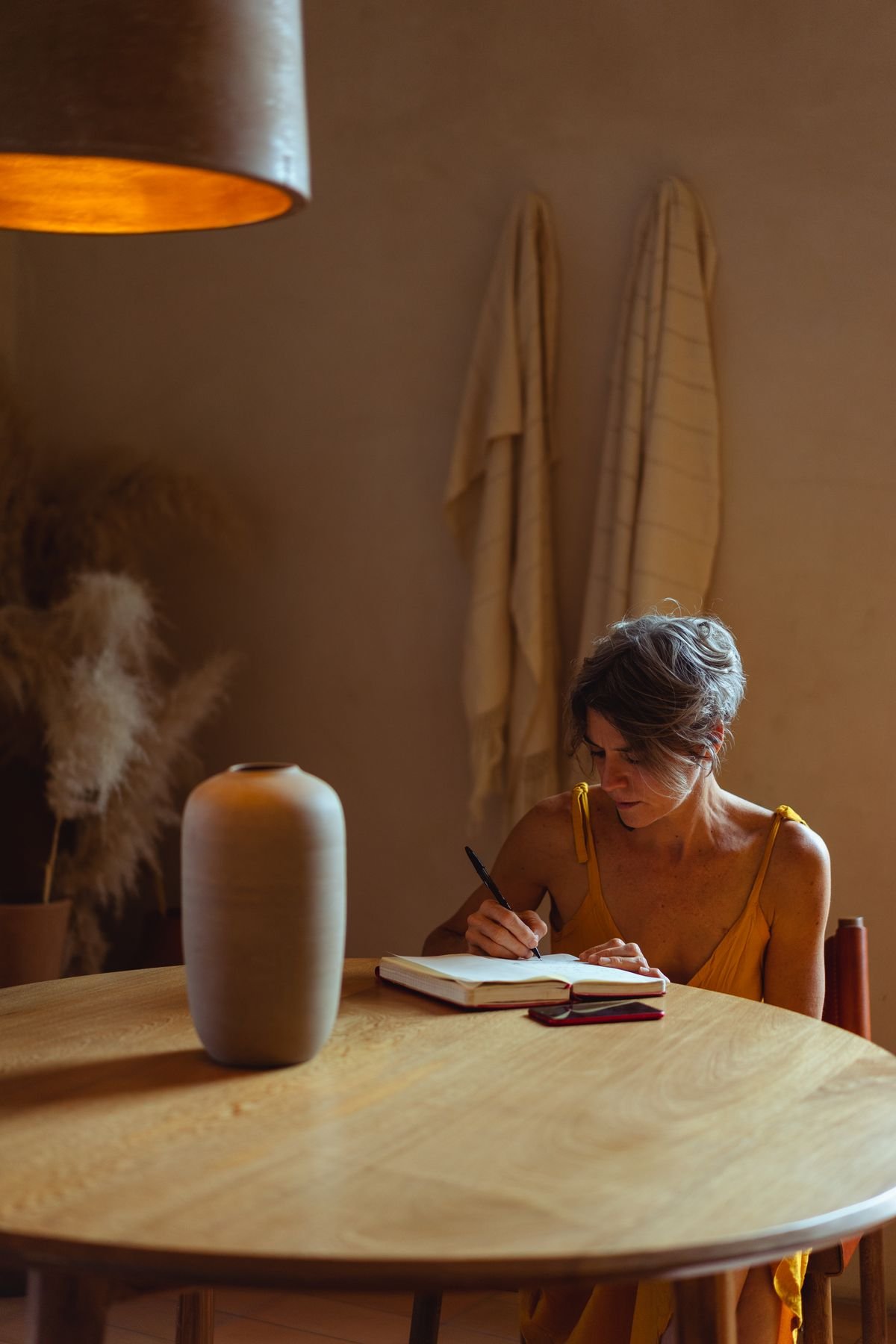 Mulher madura escrevendo em um caderno em ambiente aconchegante de home office