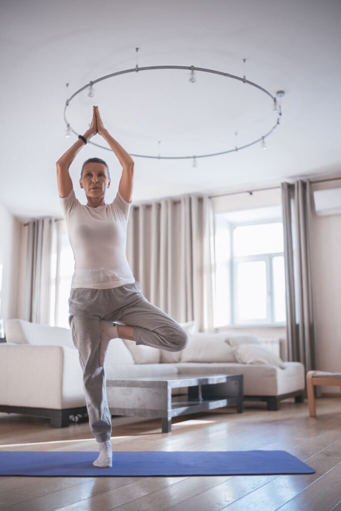 Mulher madura em postura de equilibrio durante exercicio, sala iluminada