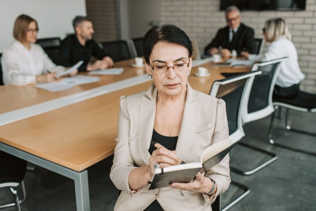 Mulher madura anotando durante uma reuniao de trabalho